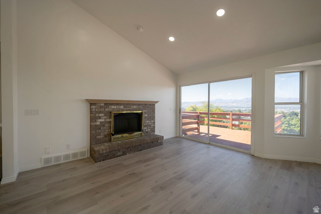 11922 Bluff View Drive Sandy, UT 84092 - Photo 6 of 30 Unfurnished living room featuring a mountain view, a fireplace, light wood-type flooring, lofted ceiling, and recessed lighting