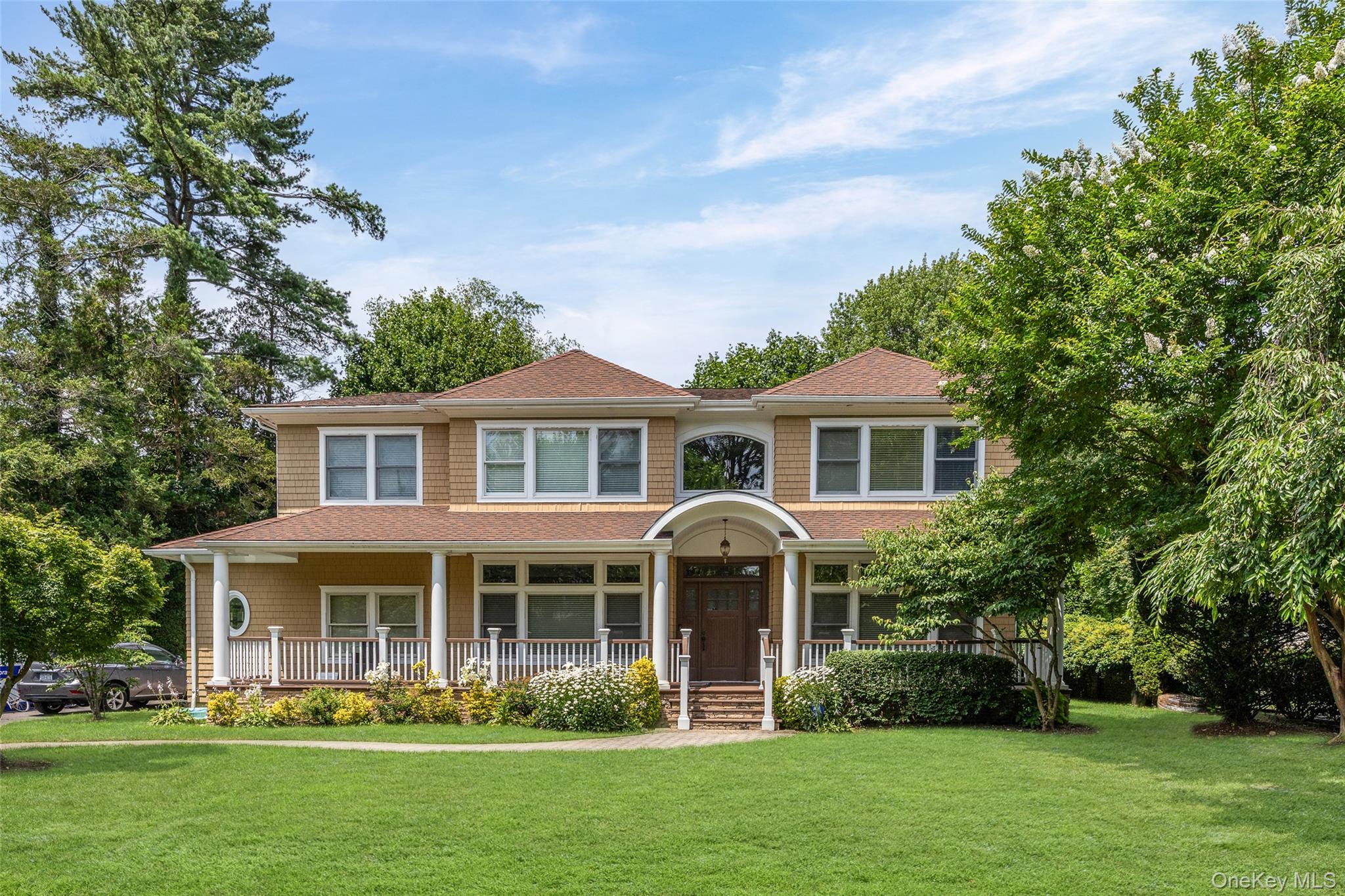 a front view of a house with a garden and trees