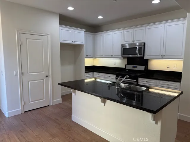 a kitchen with kitchen island granite countertop a sink a stove and refrigerator