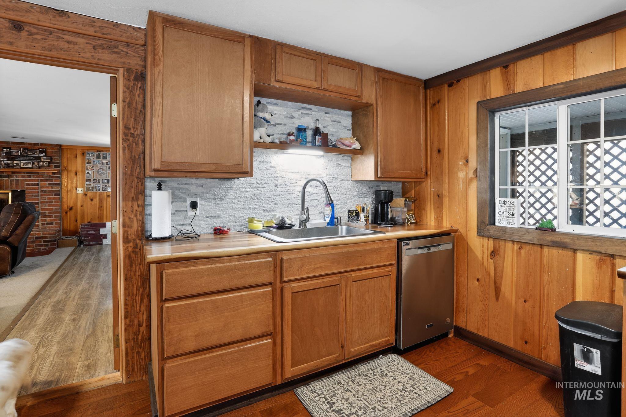 654 Bings Road Cascade, ID 83611 - Photo 13 of 40 Kitchen with wood walls, light countertops, dishwasher, dark wood-style flooring, and a brick fireplace