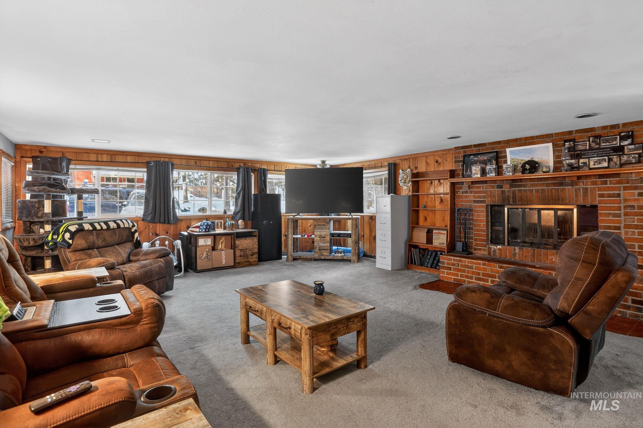 654 Bings Road Cascade, ID 83611 - Photo 8 of 40 Living area with carpet floors, wood walls, and a brick fireplace