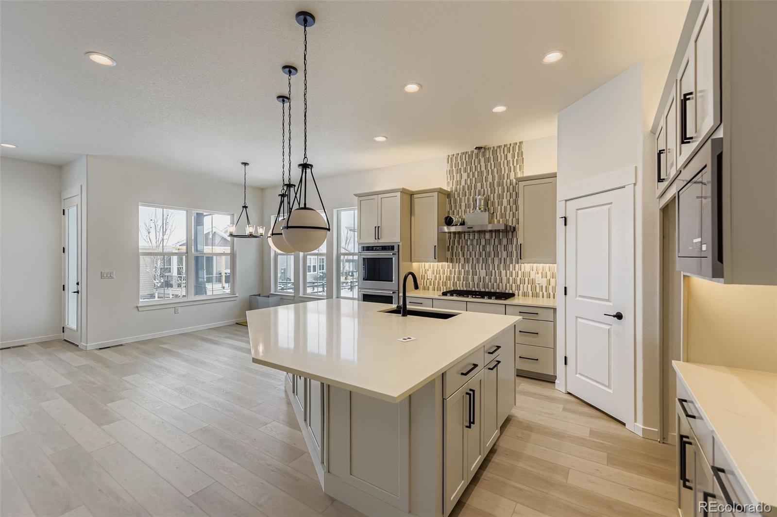 8895 South Riviera Way Aurora, CO 80016 - Photo 11 of 26 a kitchen that has a lot of cabinets in it and wooden floors