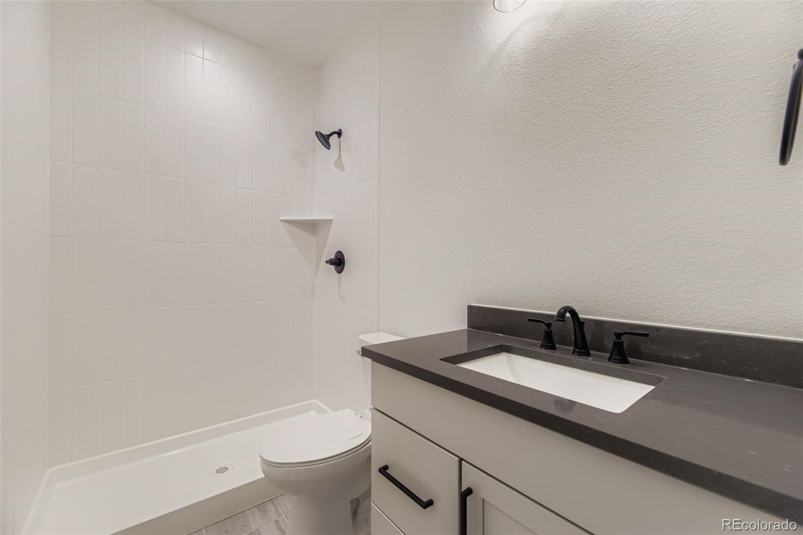 8895 South Riviera Way Aurora, CO 80016 - Photo 19 of 26 a bathroom with a granite countertop sink a toilet and a mirror