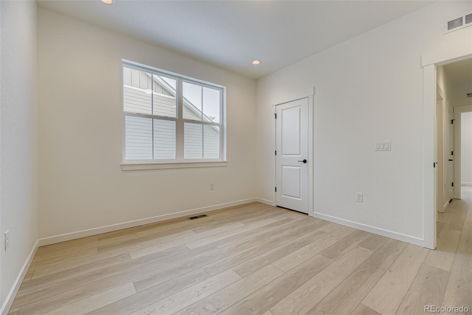 8895 South Riviera Way Aurora, CO 80016 - Photo 20 of 26 an empty room with wooden floor and windows