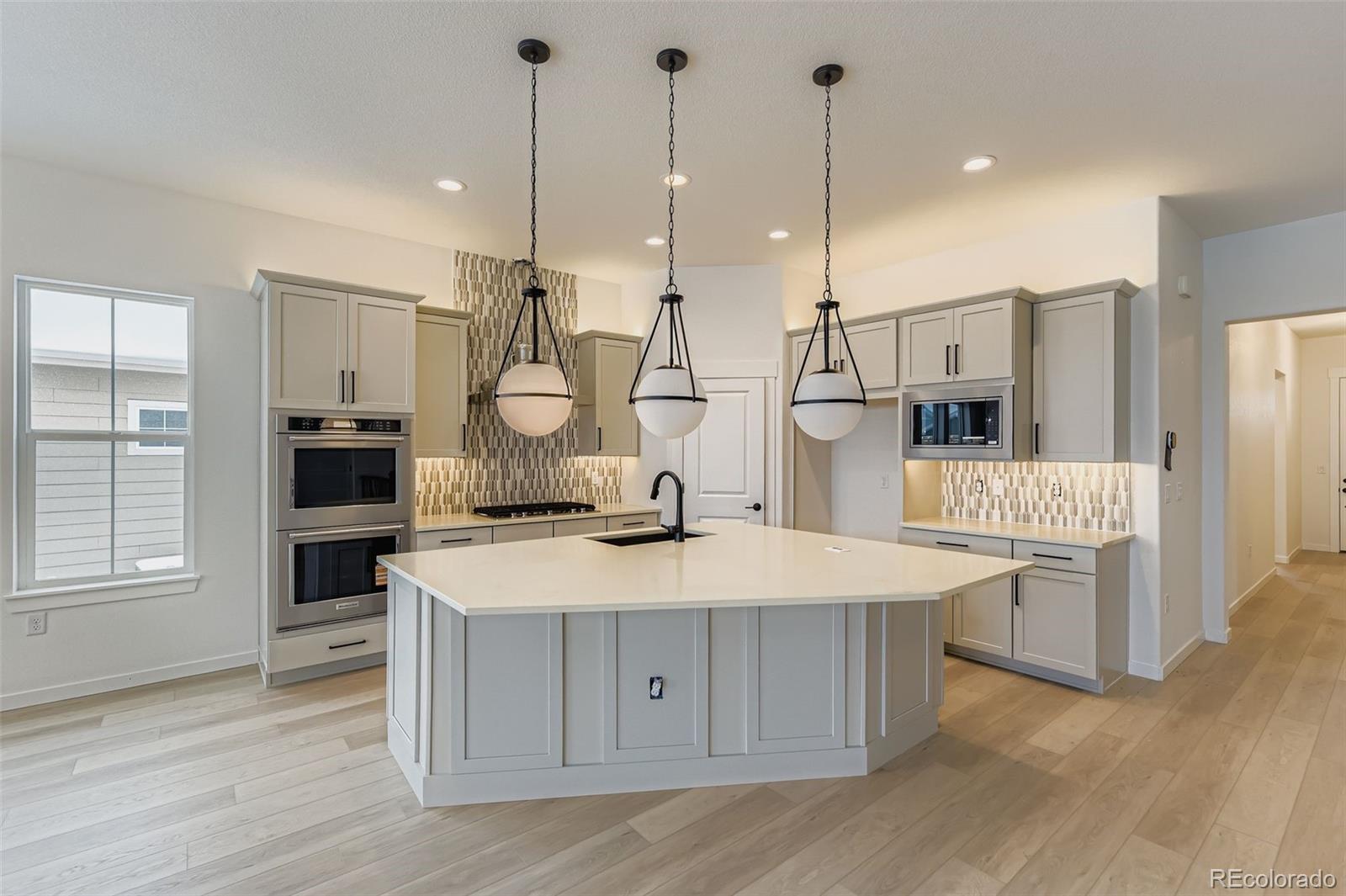 8895 South Riviera Way Aurora, CO 80016 - Photo 9 of 26 a kitchen with kitchen island a stove a sink a refrigerator and chairs