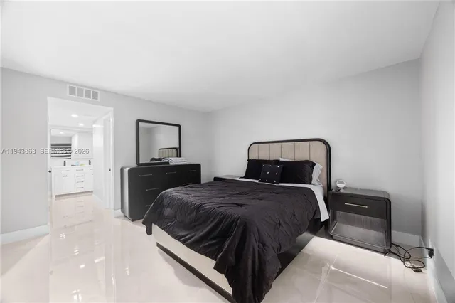 a spacious bedroom with two beds and a view of kitchen