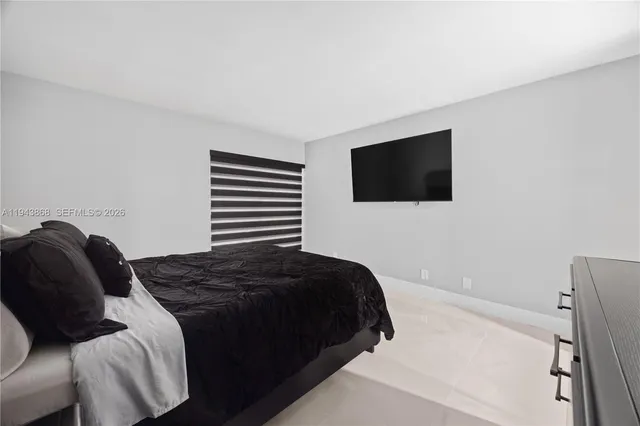 a bedroom with a bed a flat screen tv and a a white wall