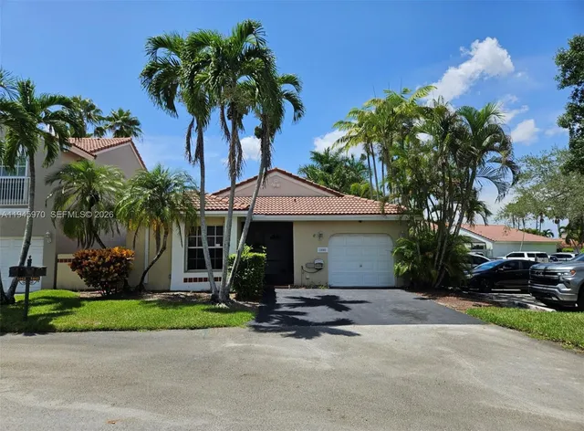 front view of a house with a yard and palm trees
