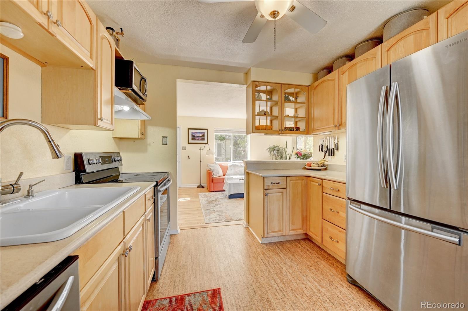 a kitchen with a refrigerator a sink dishwasher a stove and a dining table with wooden floor
