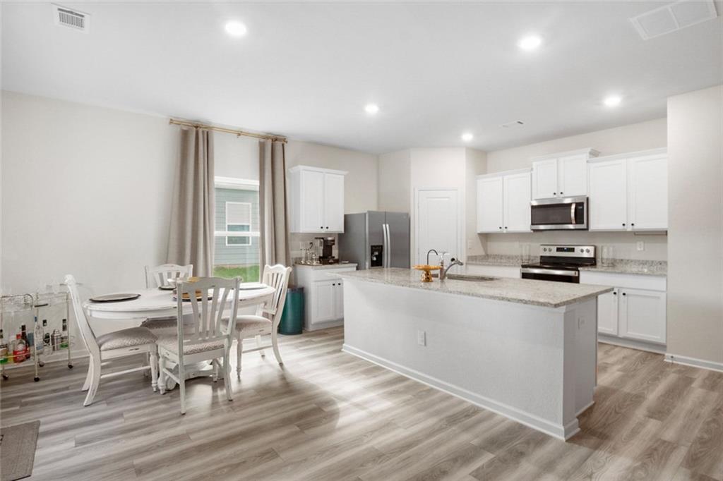 217 Limestone Circle Conyers, GA 30013 - Photo 10 of 21 a kitchen with stainless steel appliances granite countertop a stove top oven a sink a dining table and chairs with wooden floor