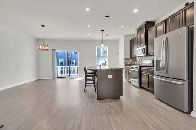 a kitchen with stainless steel appliances granite countertop a refrigerator a stove top oven a sink dishwasher and a refrigerator with wooden floor