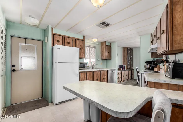 a kitchen with stainless steel appliances granite countertop a refrigerator a stove a sink dishwasher and white cabinets with wooden floor