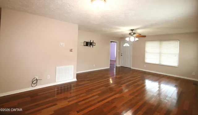 a view of an empty room and chandelier fan