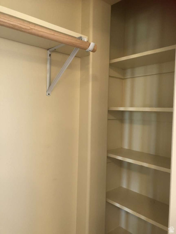 7030 West 2100 North Mendon, UT 84325 - Photo 60 of 67 Recessed closet space featuring a wood-finish hanging rod, white metal support brackets, and integrated shelving