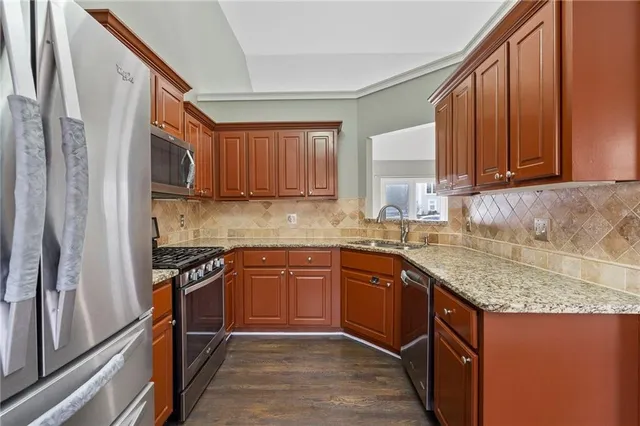 a kitchen with stainless steel appliances granite countertop wooden cabinets a stove top oven a sink and dishwasher
