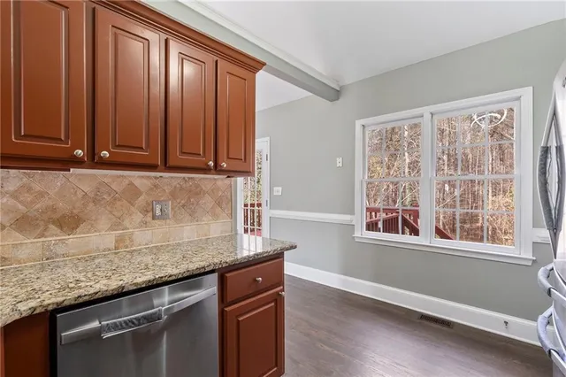 a kitchen with granite countertop cabinets stainless steel appliances wooden floor and a window