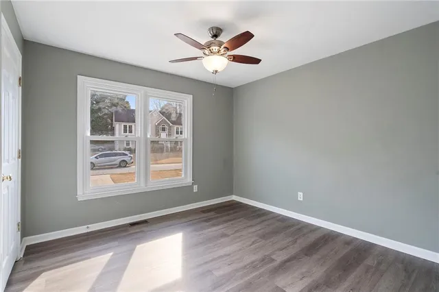 a view of an empty room with wooden floor and a window