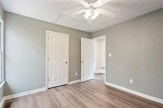 wooden floor in an empty room with a chandelier fan