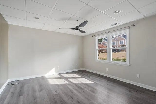 a view of an empty room with a window and wooden floor