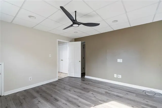an empty room with wooden floor fan and windows