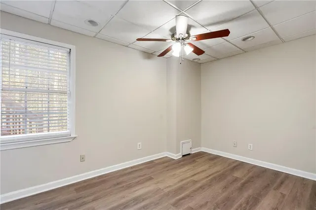 an empty room with wooden floor fan and windows