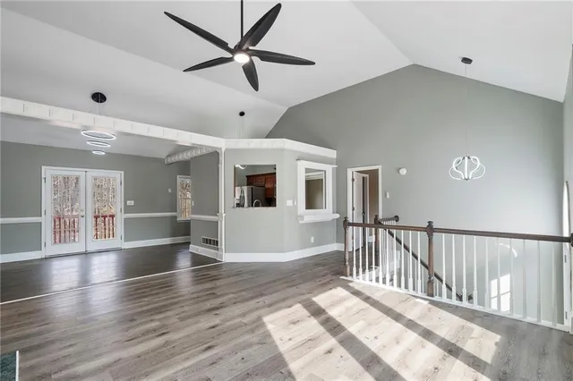 an empty room with wooden floor fan and windows