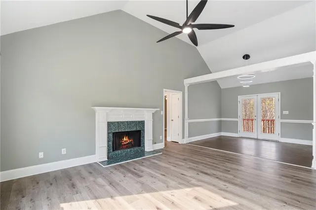 a view of an empty room with wooden floor fireplace and a window