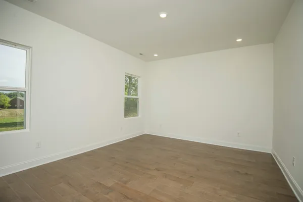 a view of kitchen with kitchen island refrigerator sink and white cabinets with wooden floor