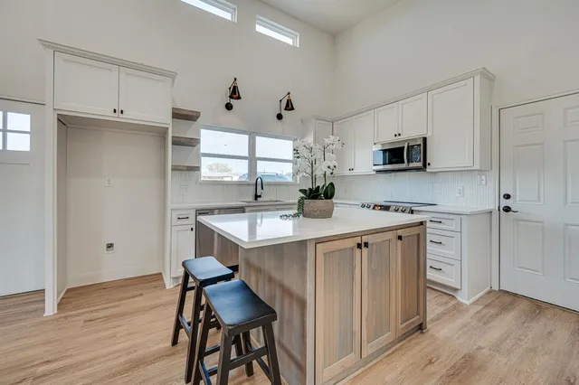 a kitchen with kitchen island white cabinets and stainless steel appliances