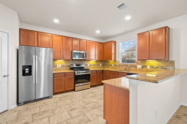 a kitchen with granite countertop a refrigerator stove top oven and sink