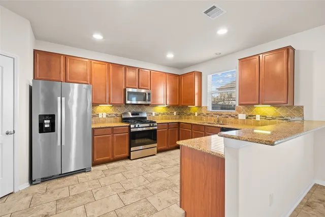 a kitchen with granite countertop a refrigerator stove top oven and sink