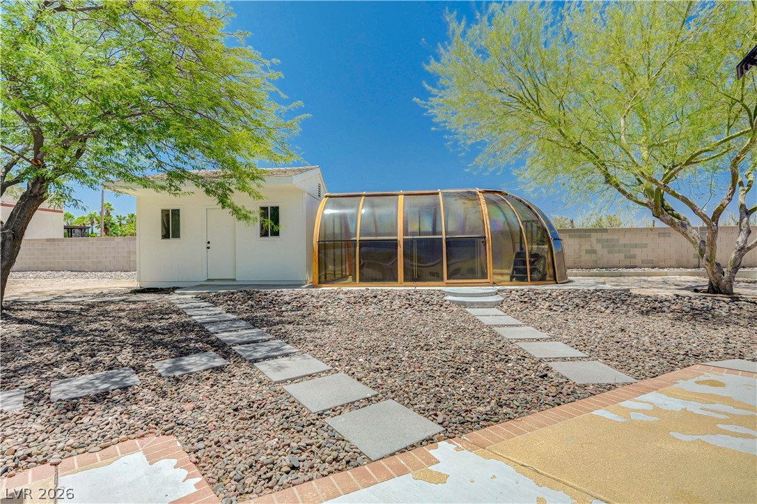 7631 Bermuda Road Las Vegas, NV 89123 - Photo 34 of 64 A tranquil outdoor space offers a private outbuilding and a unique, covered pool enclosure amidst natural landscaping.