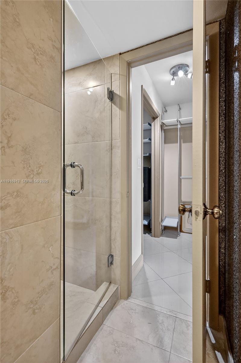 4000 Towerside Terrace, Unit 1612 Miami, FL 33138 - Photo 23 of 49 a bathroom with a glass shower door and a mirror