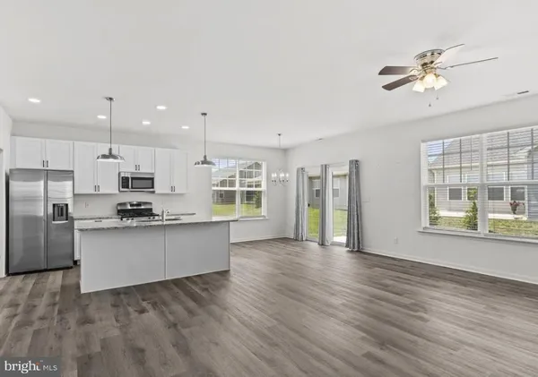 a kitchen with stainless steel appliances granite countertop a refrigerator a sink dishwasher a stove and a wooden floors