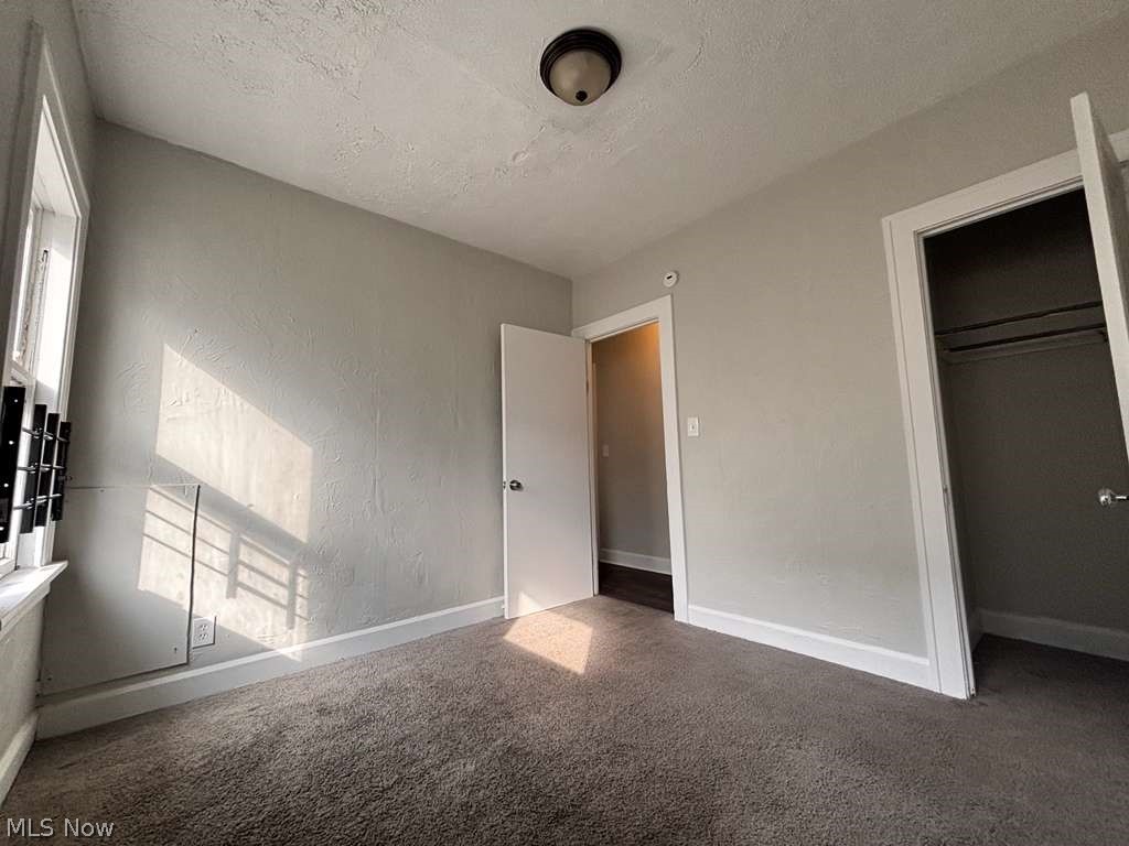 907 Rondel Road Cleveland, OH 44110 - Photo 12 of 26 Carpeted room with light grey walls, white trim, and a window with a black bracket fixture