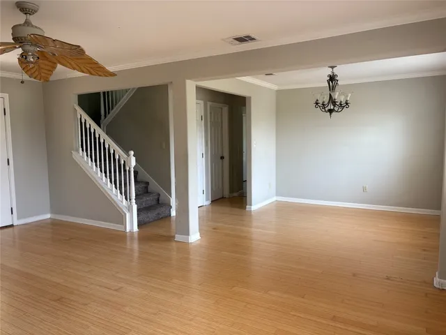 a view of a hallway view with wooden floor and a ceiling fan