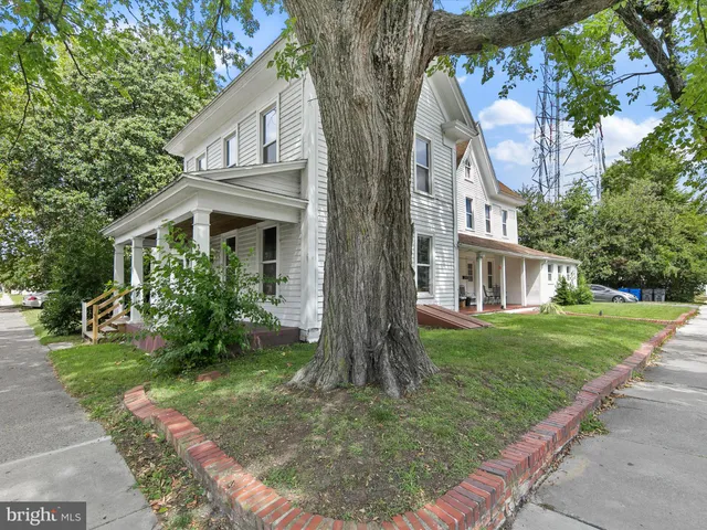 a view of a house with a big yard and large trees