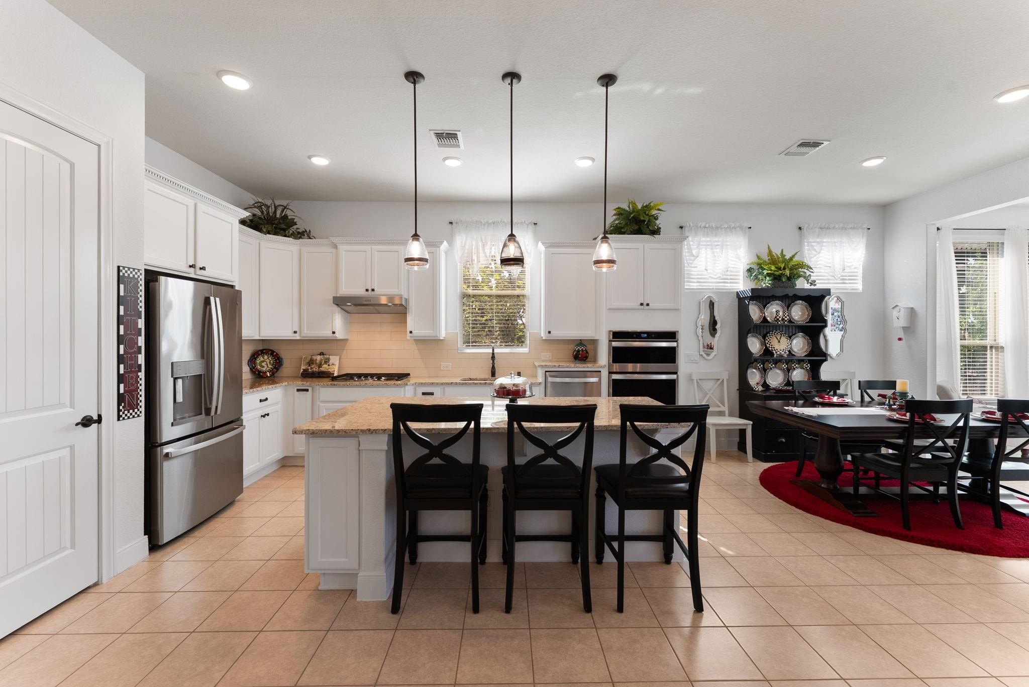 230 Galloway Court Spring, TX 77382 - Photo 16 of 32 a kitchen with kitchen island granite countertop a table chairs microwave and refrigerator