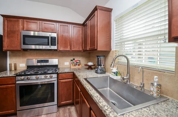 a kitchen with stainless steel appliances granite countertop a stove a sink and a microwave