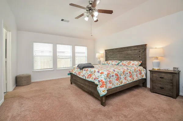 a bed sitting in a bedroom next to a window and a chandelier