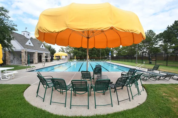 a view of a swimming pool with lawn chairs under an umbrella