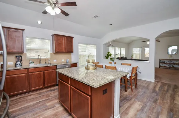 a kitchen with stainless steel appliances granite countertop wooden cabinets a dining table and chairs