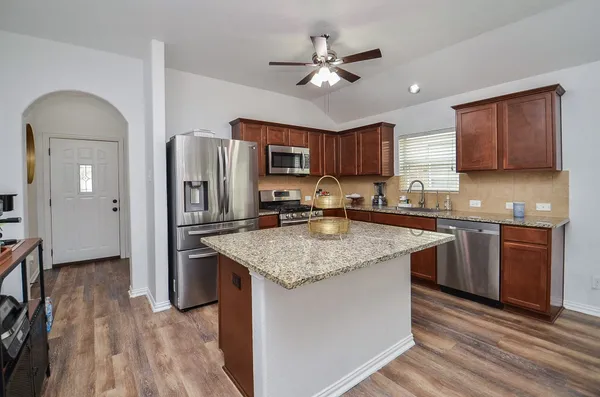 a kitchen with stainless steel appliances granite countertop a sink refrigerator and cabinets
