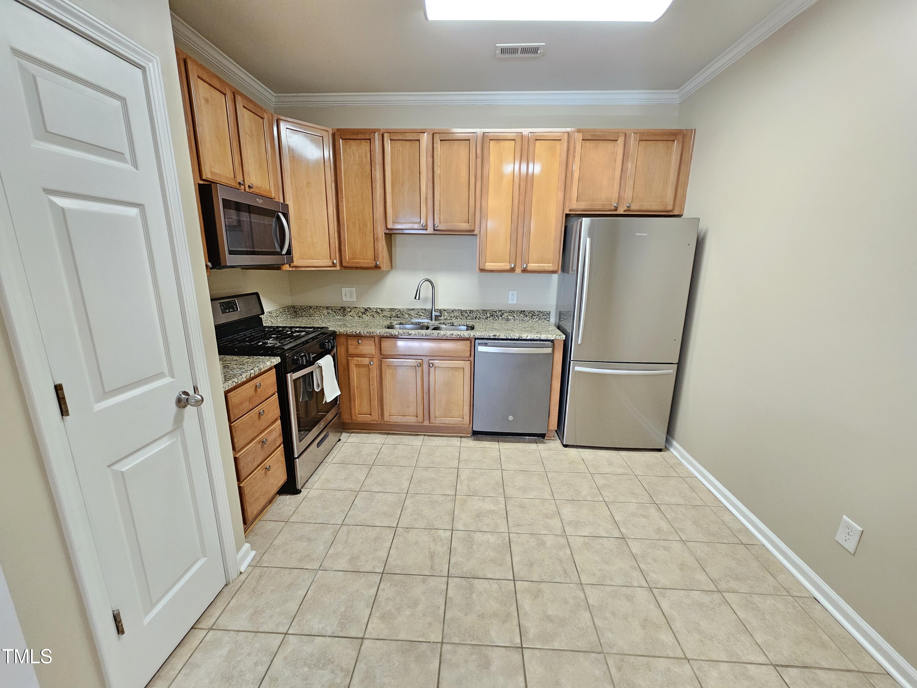 2220 Valley Edge Drive, Unit 107 Raleigh, NC 27614 - Photo 11 of 24 a kitchen with granite countertop a refrigerator a sink a stove top oven and cabinets