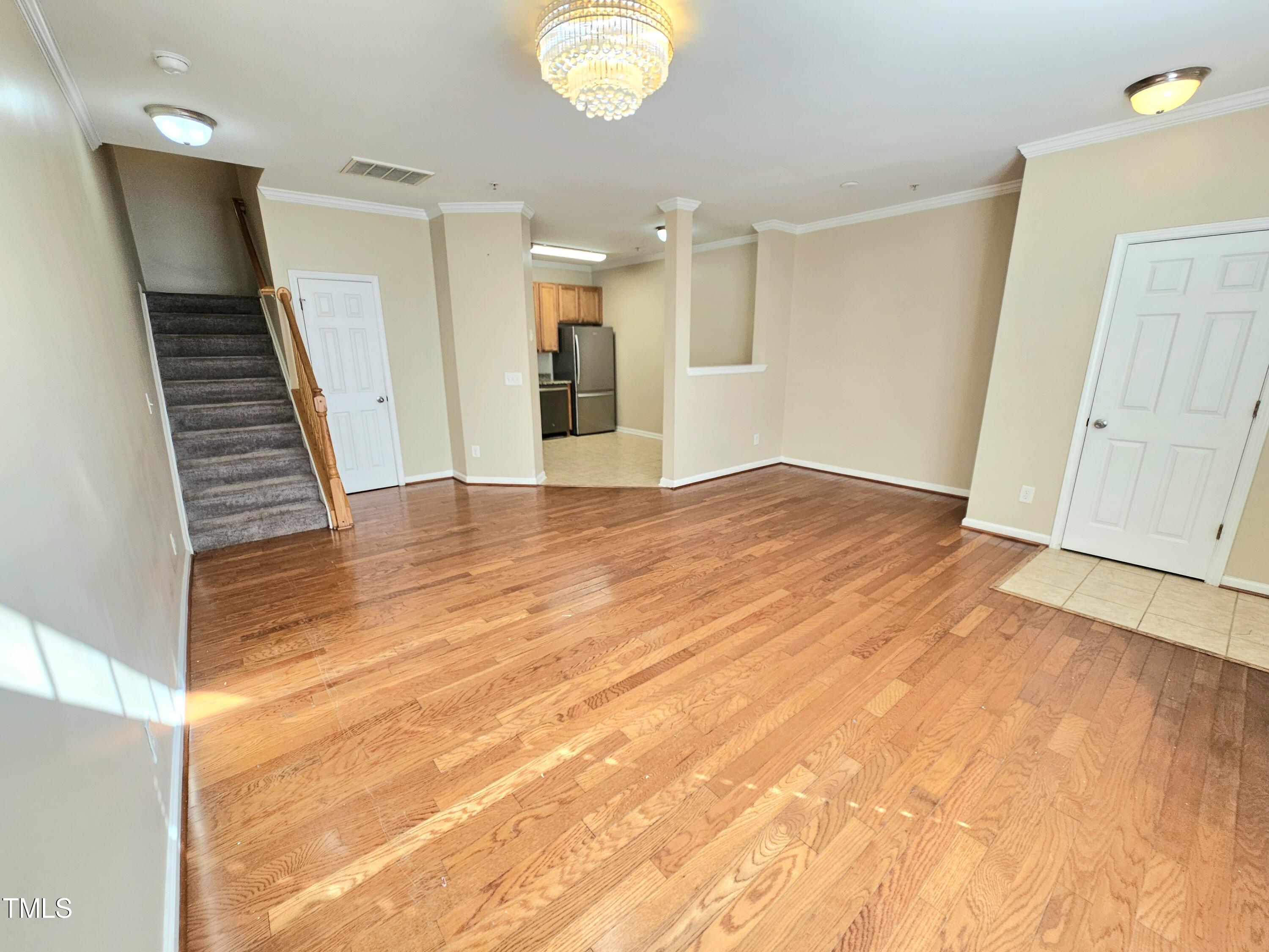 2220 Valley Edge Drive, Unit 107 Raleigh, NC 27614 - Photo 5 of 24 a view of an empty room with wooden floor and a kitchen