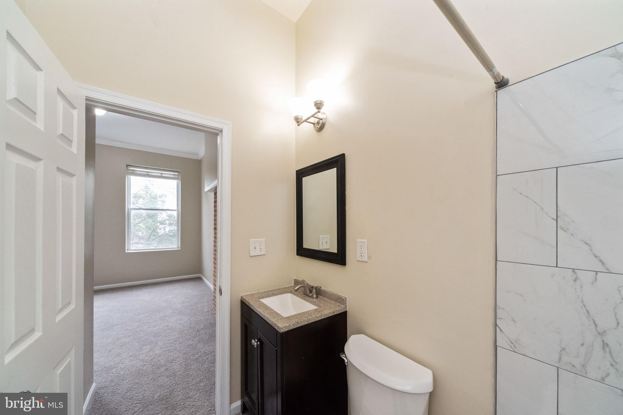 1708 Madison Avenue Baltimore, MD 21217 - Photo 40 of 56 a bathroom with a toilet sink vanity and mirror