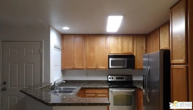 a kitchen with stainless steel appliances granite countertop a refrigerator a stove and a sink with wooden floor