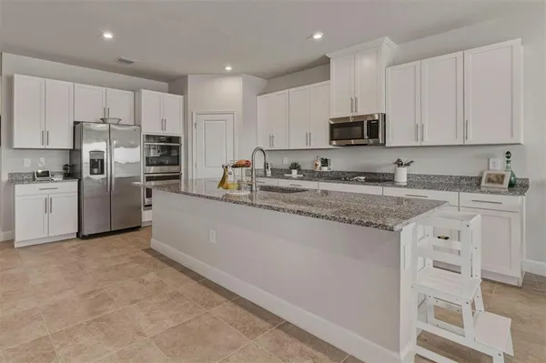 a kitchen with stainless steel appliances granite countertop a stove top oven a refrigerator a sink and cabinets
