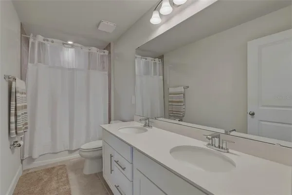 a bathroom with a double vanity sink toilet and a mirror