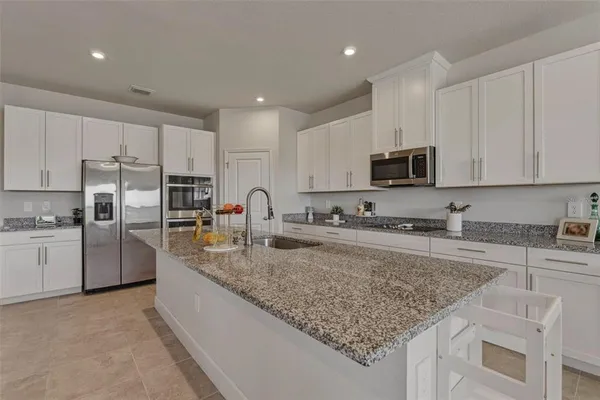 a kitchen with granite countertop a sink a counter top space stainless steel appliances and cabinets